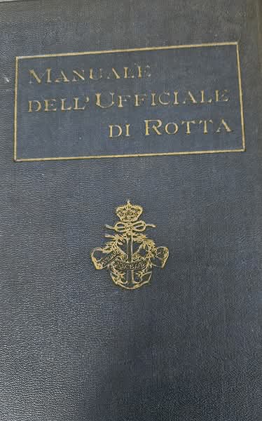 Copertina rigida in pelle scura del libro Manuale dell'Ufficiale di Rotta con stemma dorato e motto Navigare Necesse